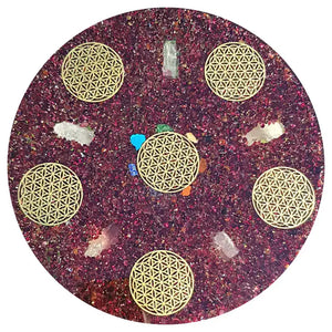 Sous-verre circulaire en résine avec une fleur dorée incrustée aux motifs de « fleur de vie » et des pierres précieuses éparpillées.